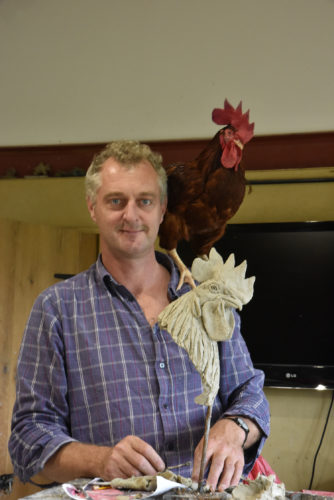 Hamish with chicken on his shoulder and chicken head sculpture