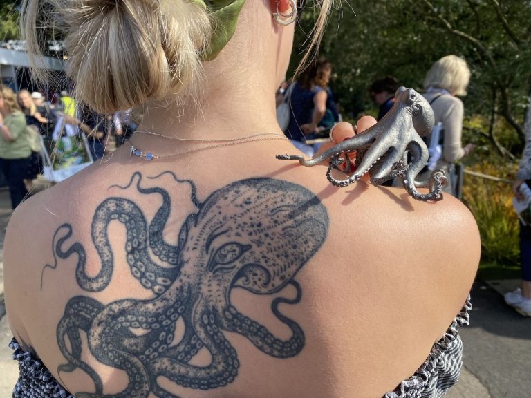 octopus sculpture on woman's shoulder with octopus tattoo