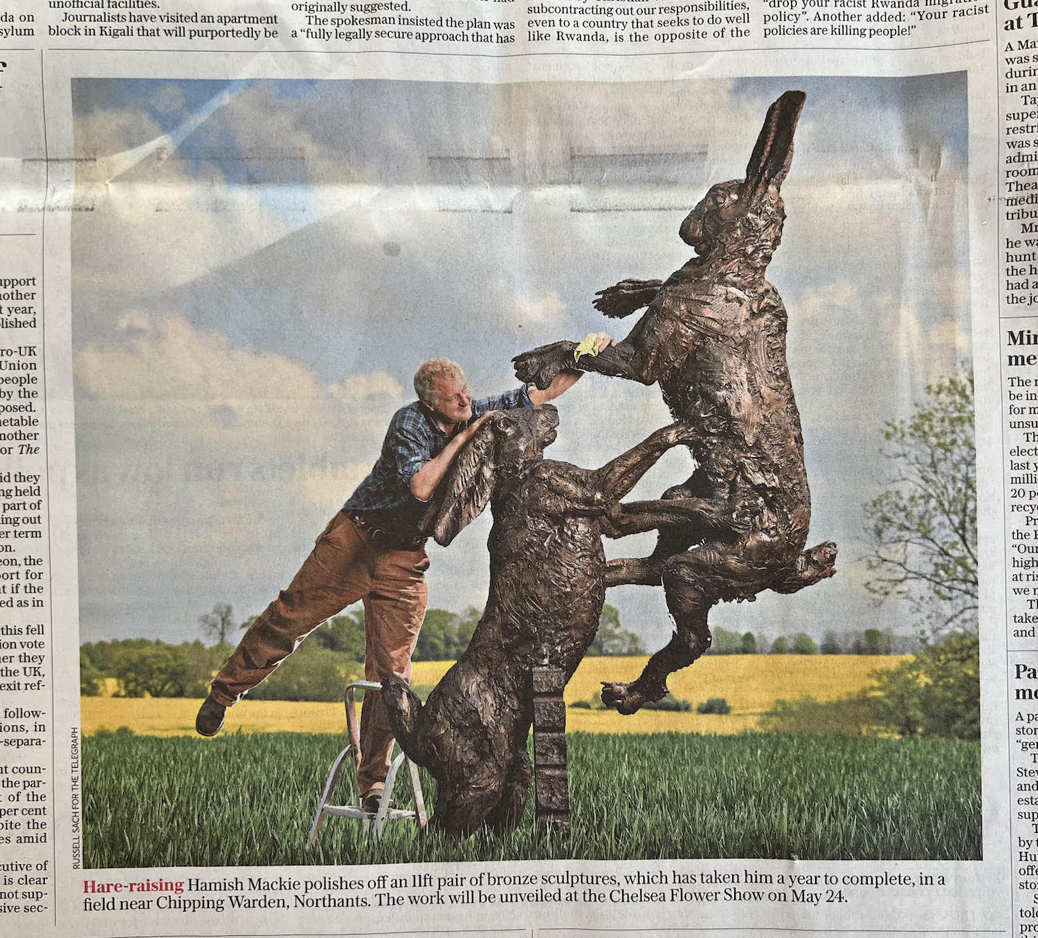 Hamish cleaning hares monumental sculpture in field